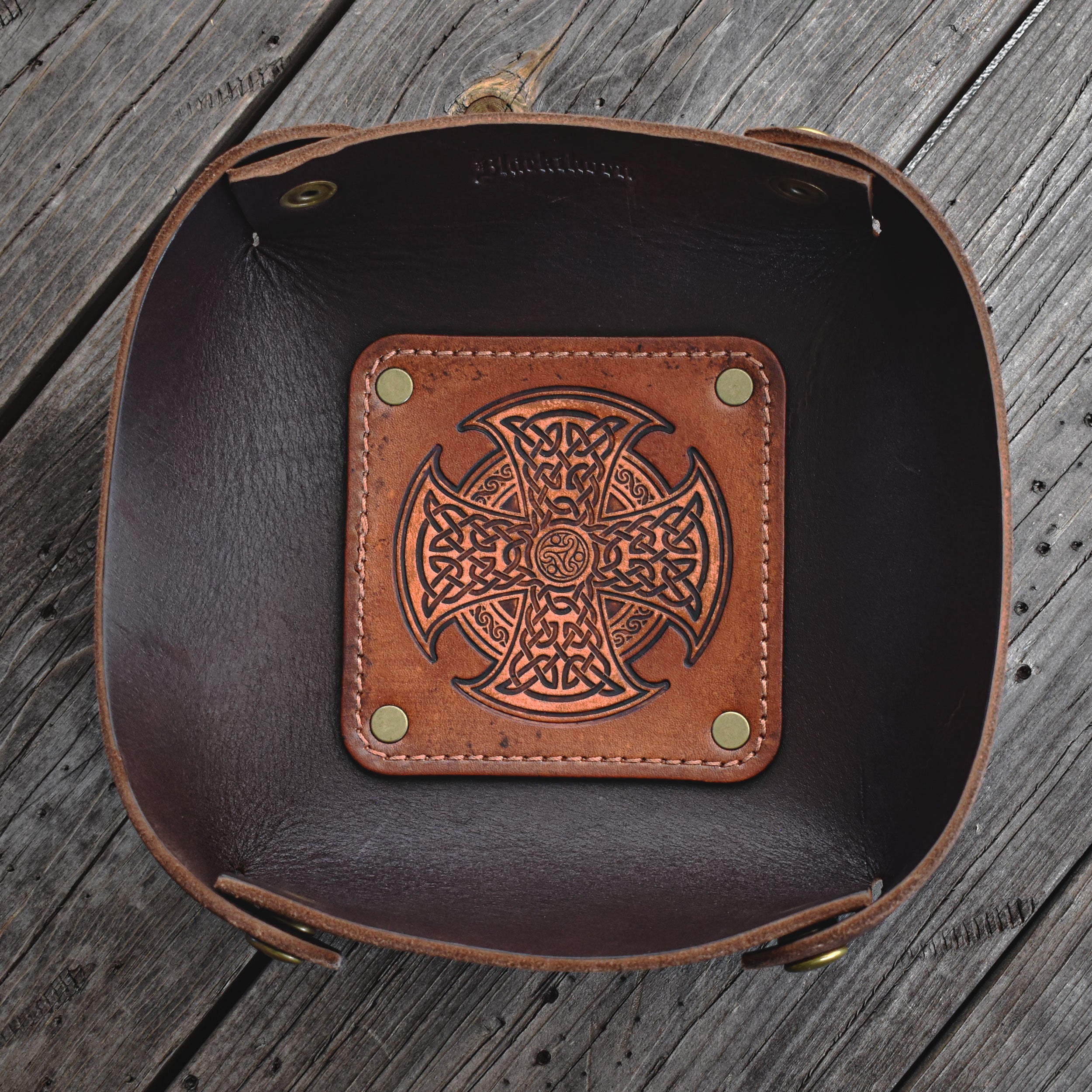 Brown leather valet tray with Celtic knot design on a wooden surface
