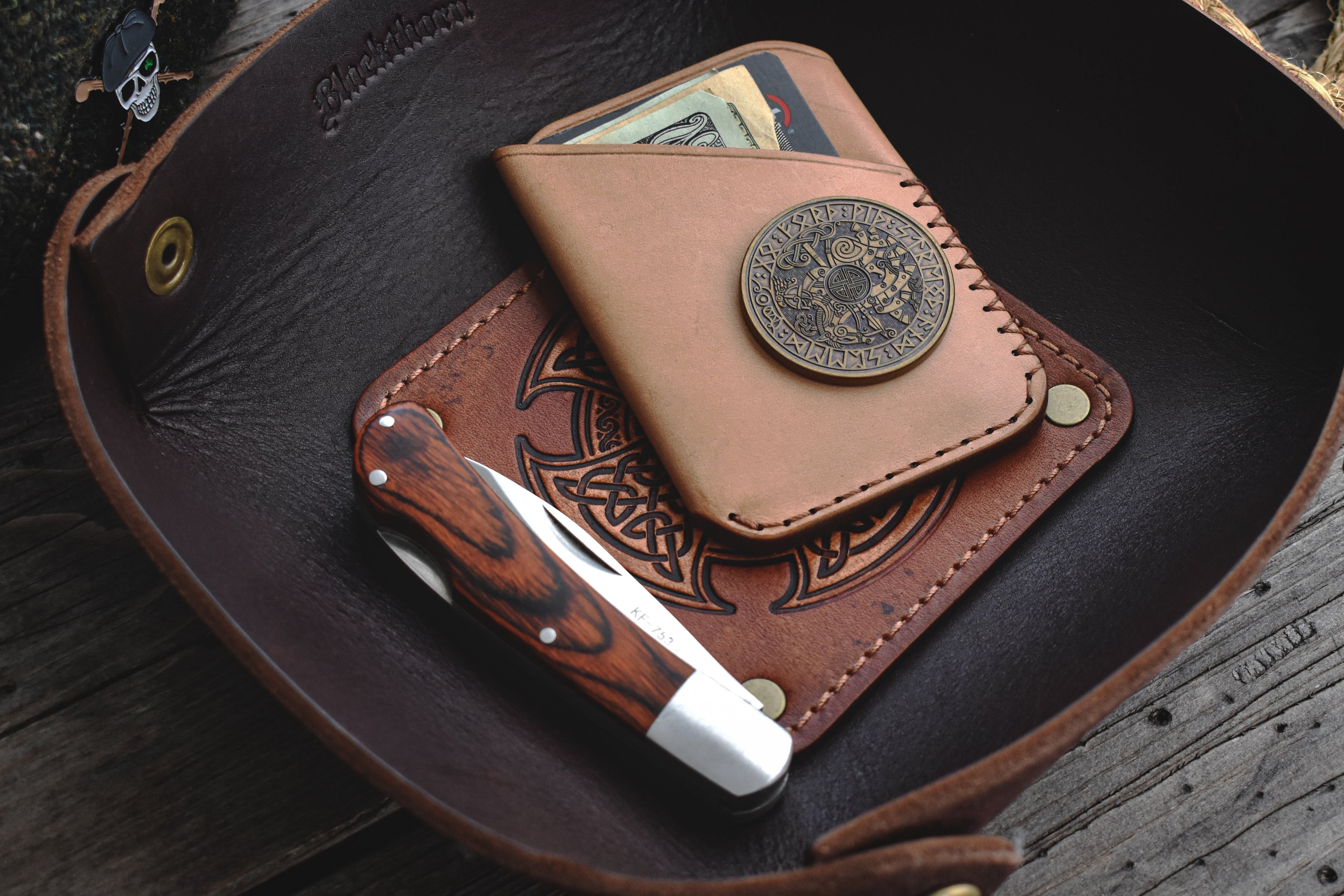 Brown leather valet tray with Celtic knot design on a wooden surface