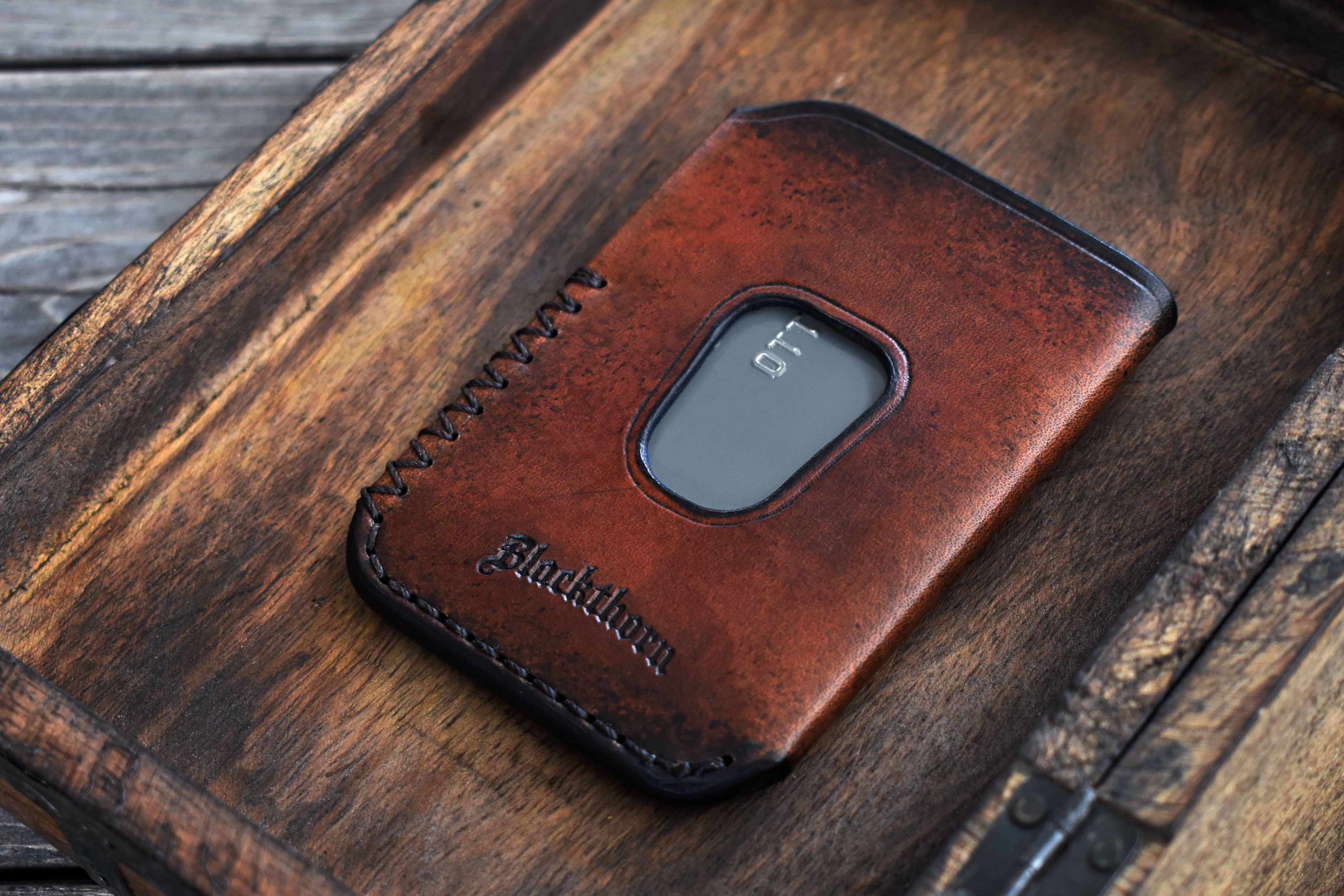 Brown leather wallet with 'Blackthorn' branding on a wooden surface