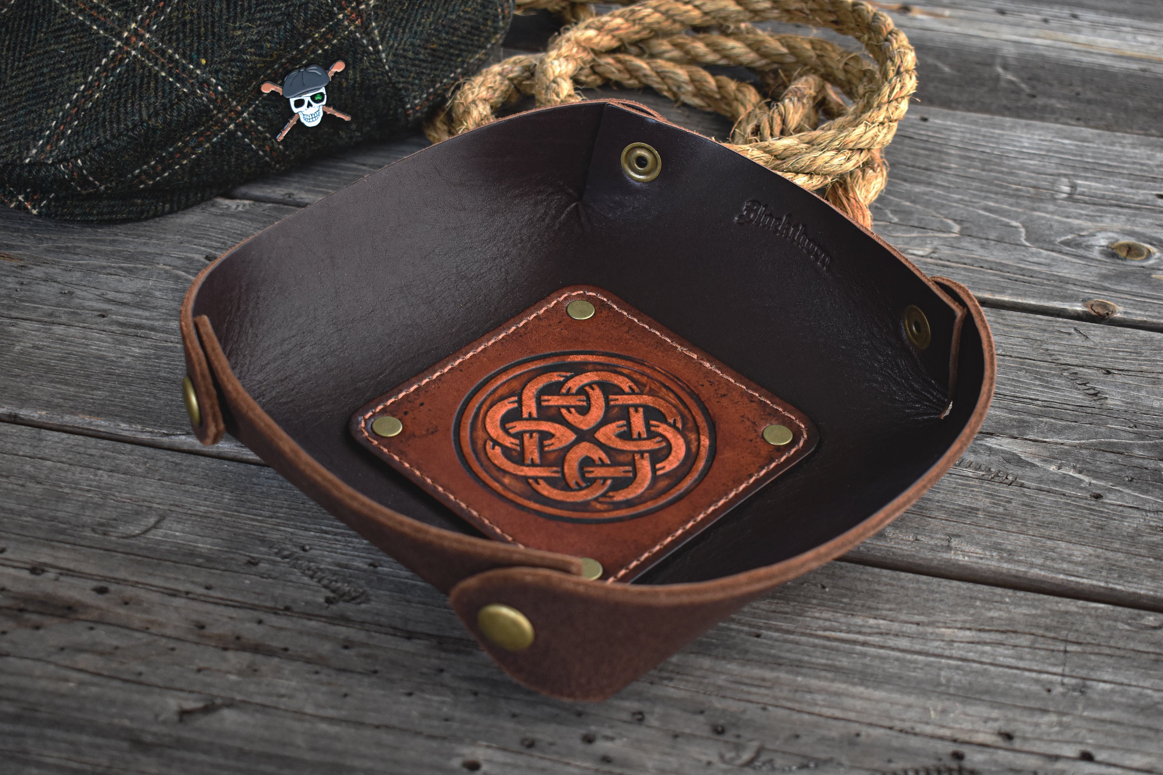 Brown leather tray with Celtic knot design on a wooden surface