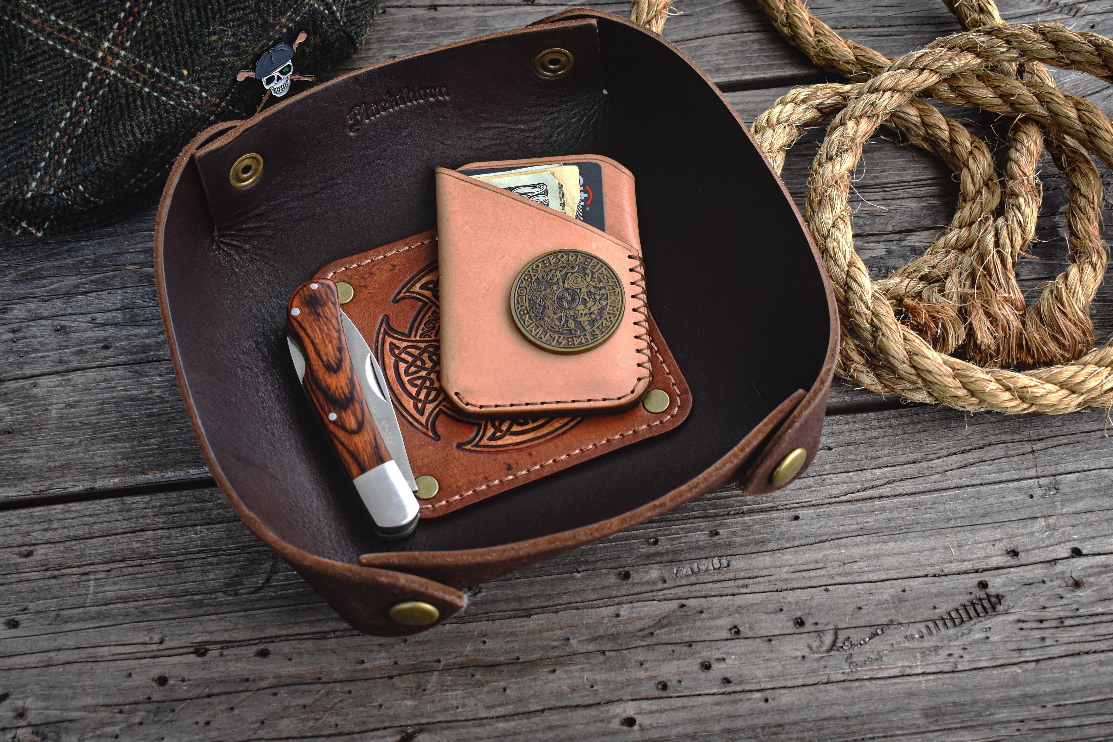 Brown leather valet tray with Celtic knot design on a wooden surface
