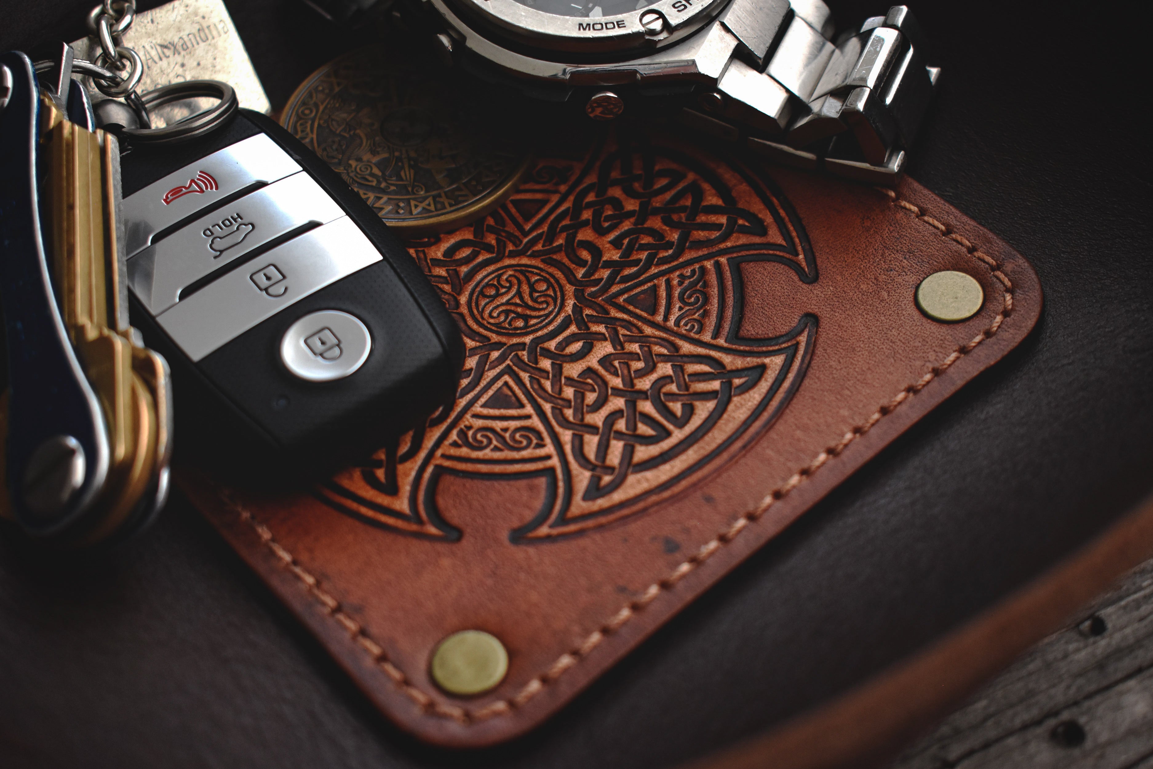 Brown leather valet tray with Celtic knot design on a wooden surface